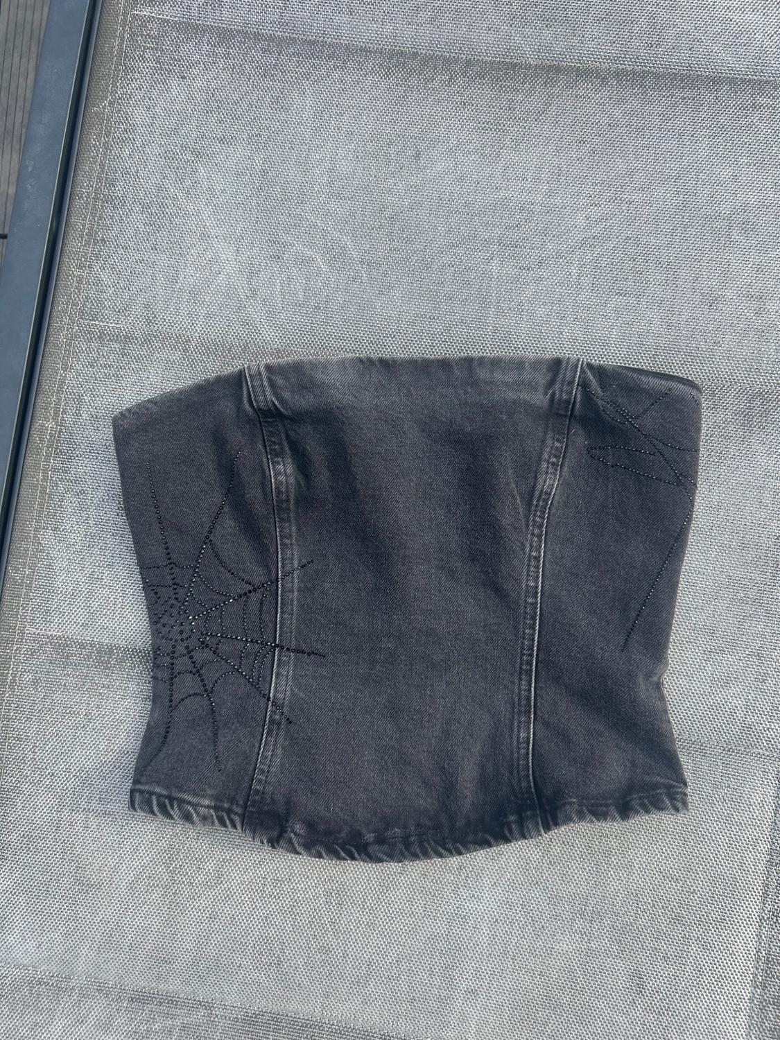 Dark grey strapless denim corset top with black rhinestone cobwebs on the sides, over a mesh surface.