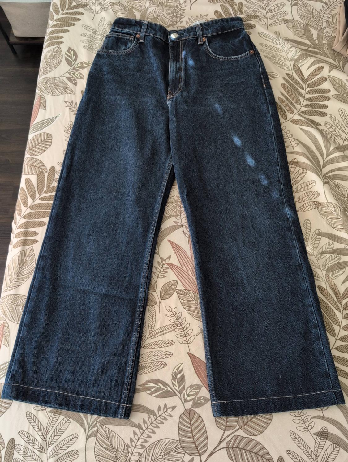 Dark blue wide-leg jeans on a leaf-print surface.