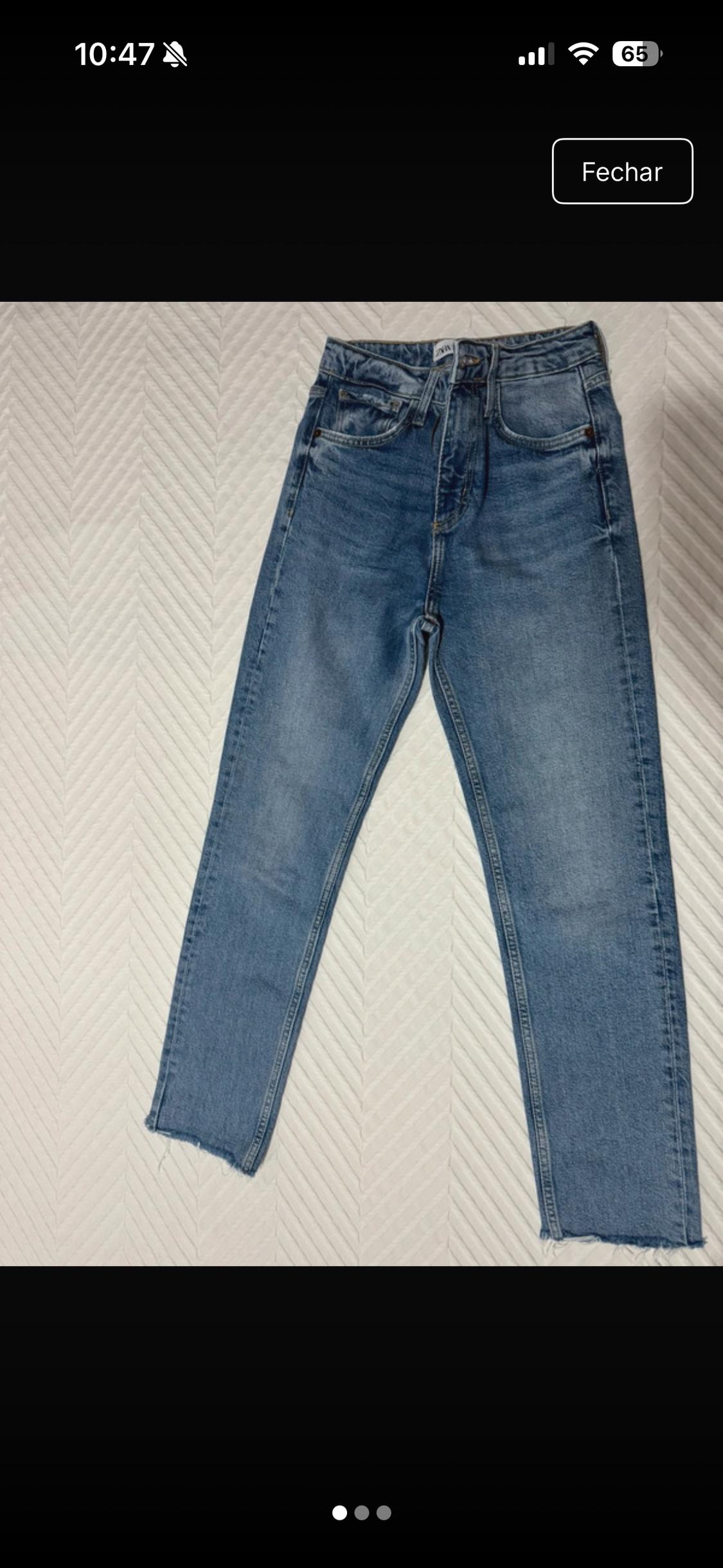 High-waisted blue jeans with frayed hems on a textured white fabric. Text: 10:47 65 Close.