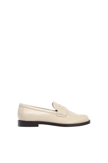 Beige loafer with a black sole on a white background. Classic and elegant design, ideal for a sophisticated look.