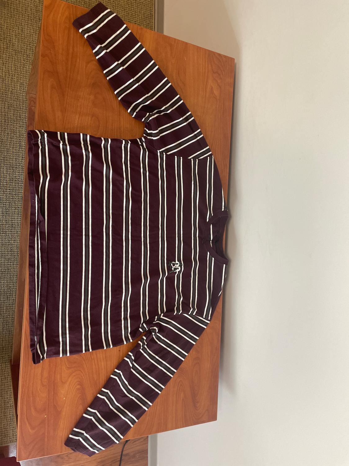 Black and white horizontal striped long-sleeved T-shirt on a brown background, placed on a wooden table.