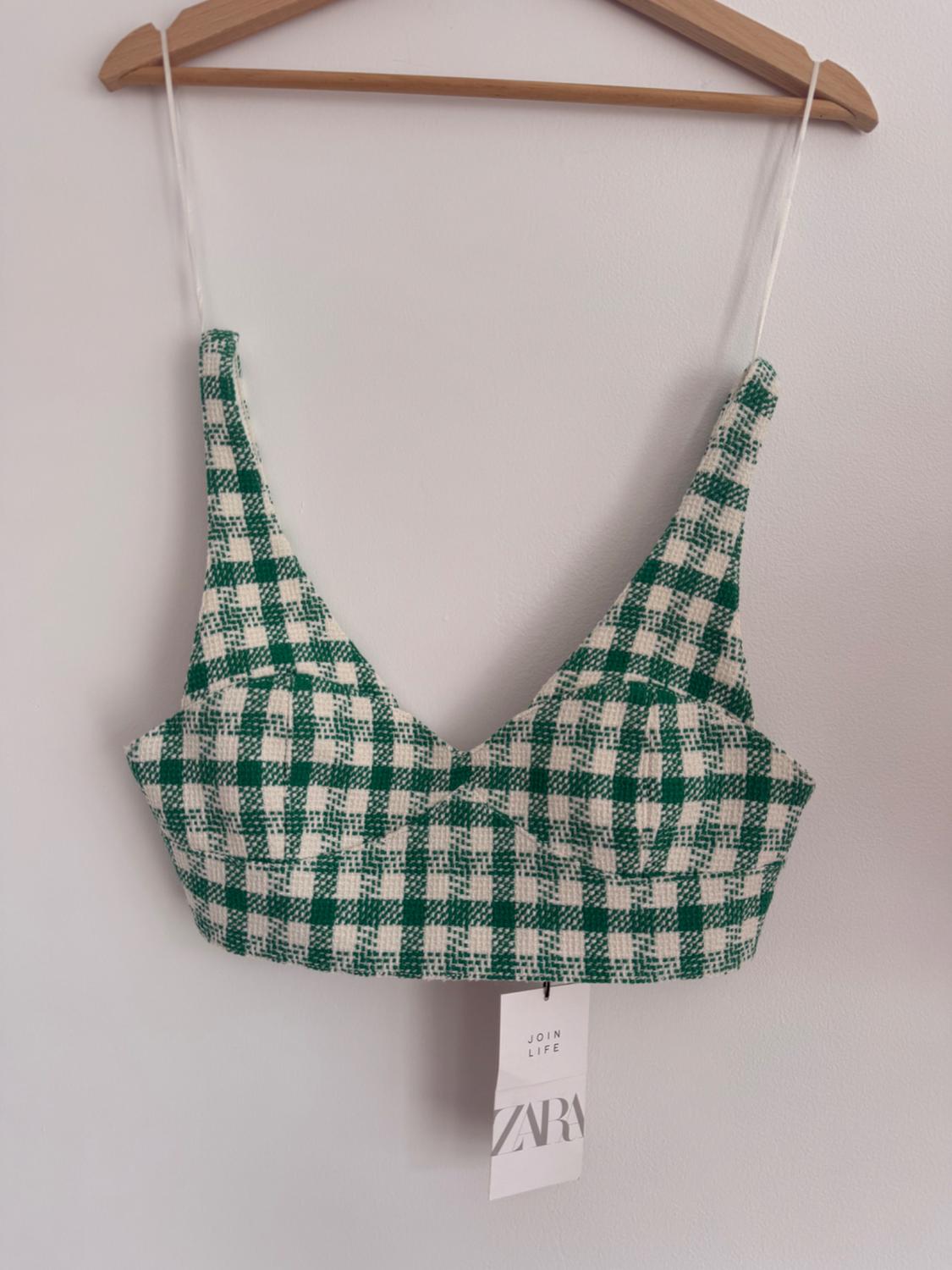 Green and white checked top hanging on a wooden hanger. Label visible with text: "JOIN LIFE ZARA". White background.