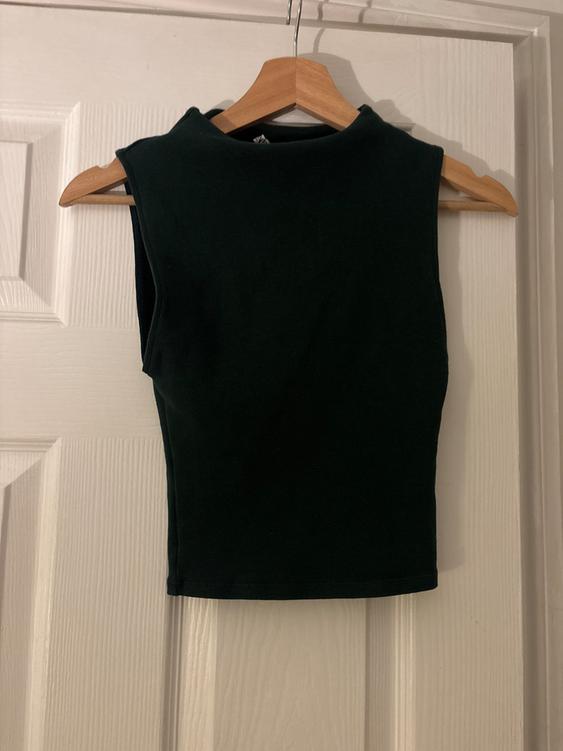 Black sleeveless top hanging on a wooden hanger over a white door.