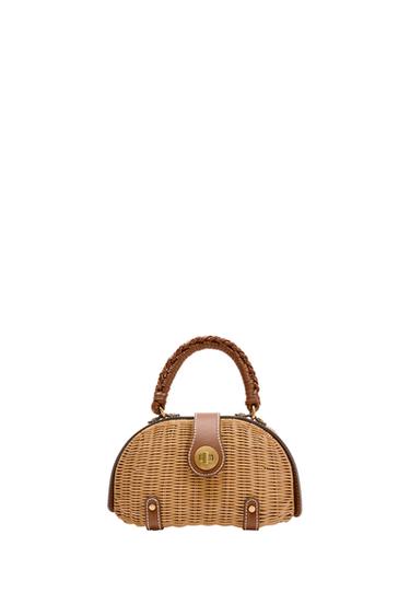 Front view of brown bag with braided handle and gold metal clasp. Wicker design with faux leather details.
