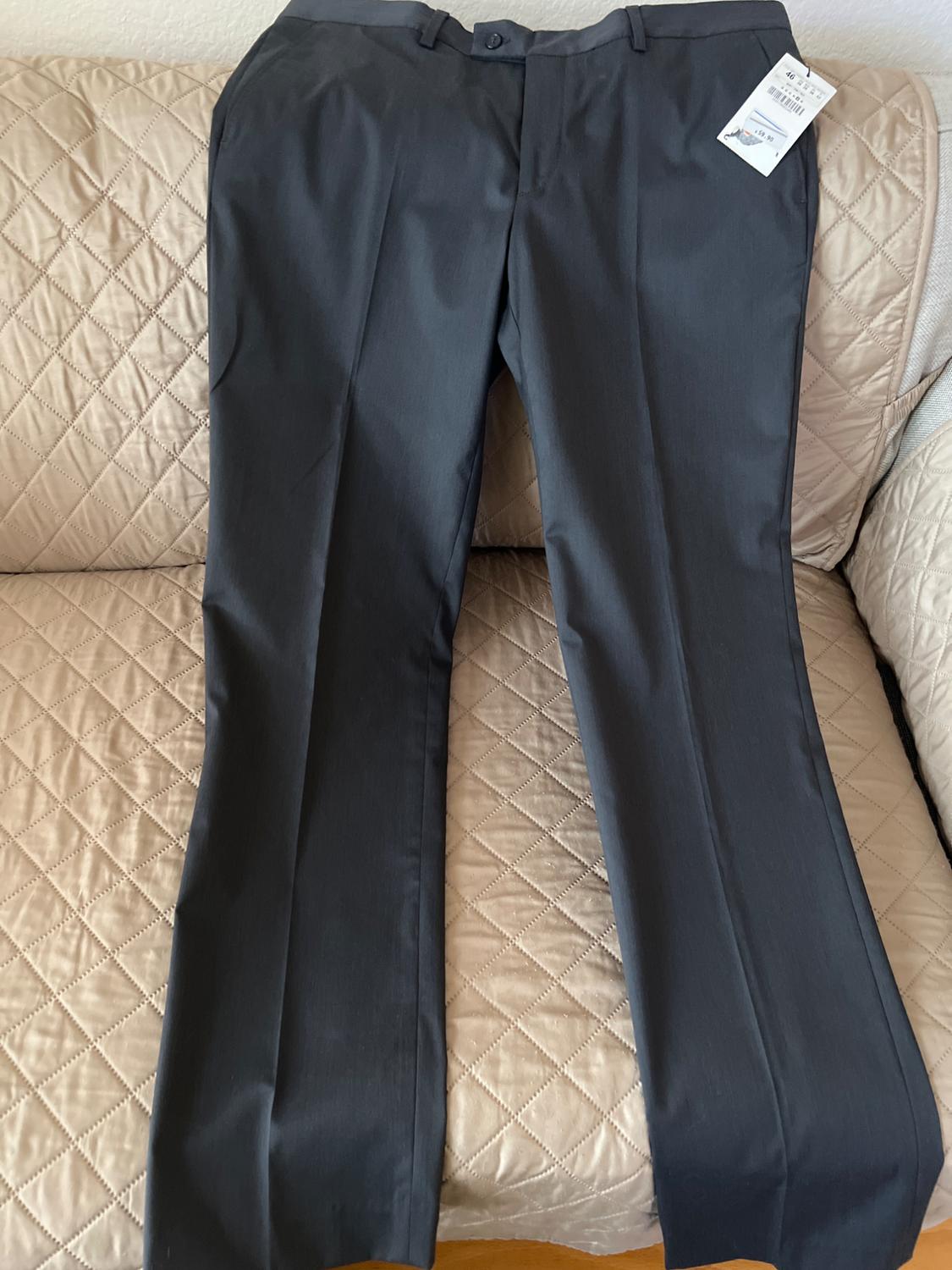 Dark gray pants with a tag, placed on a beige sofa with a diamond pattern.