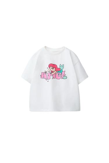 Front view of a white T-shirt with an Ariel print and "Ariel" text in pink. Round neck and short sleeves.
