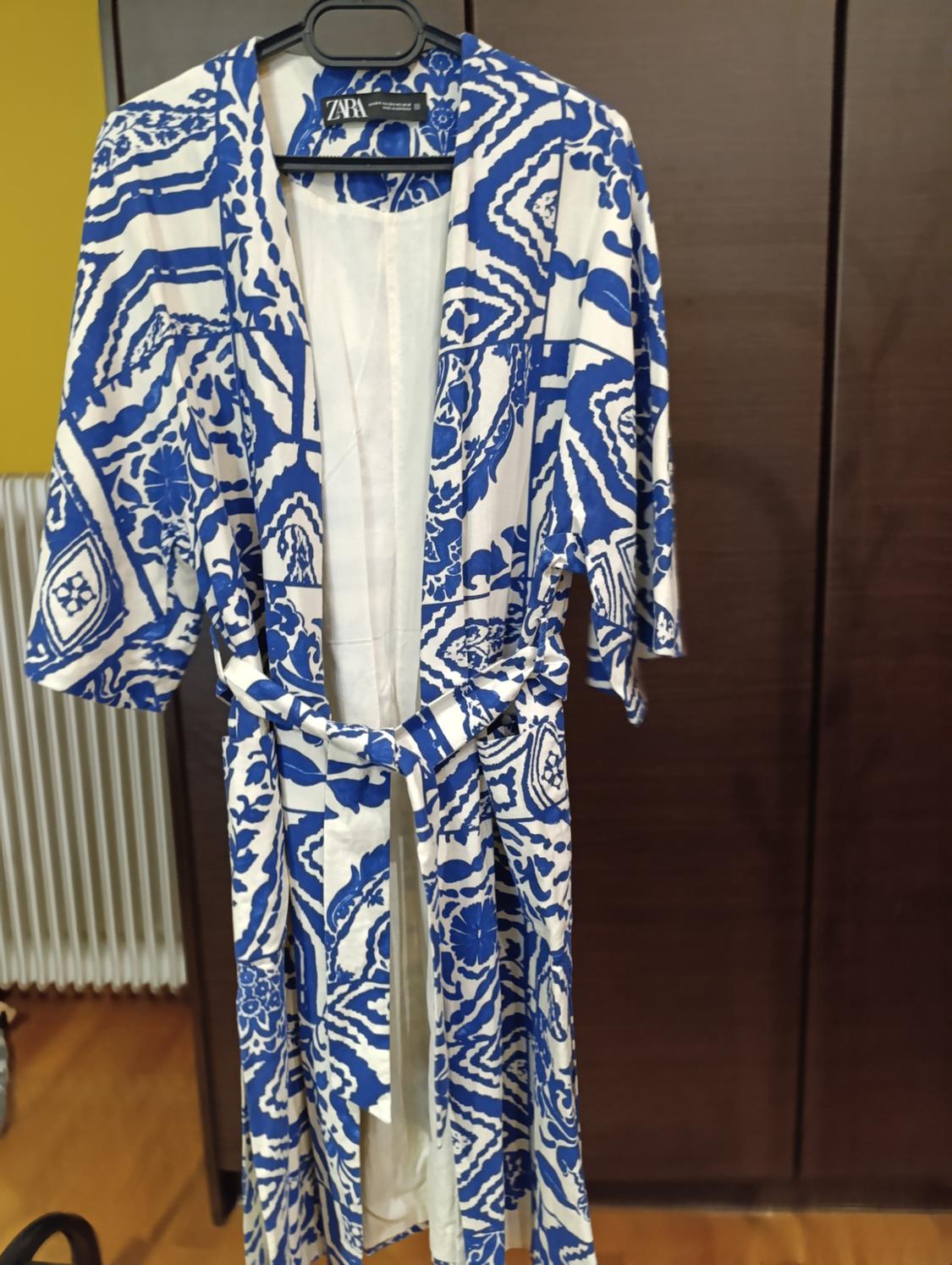 Blue and white patterned dressing gown, matching belt, on a wooden background and yellow wall. Visible label: ZARA.