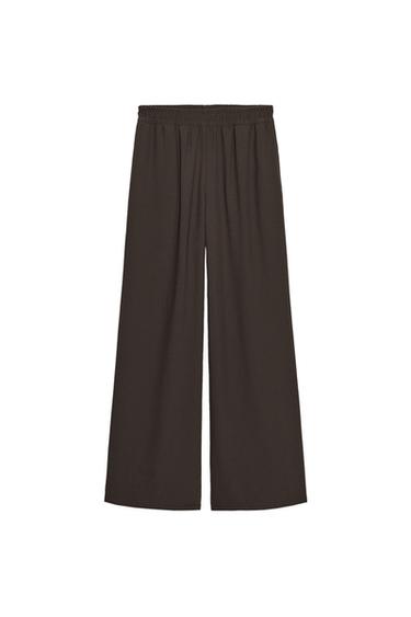 Front view of brown wide-leg trousers with a high rise and elasticated waistband with hidden side pockets.