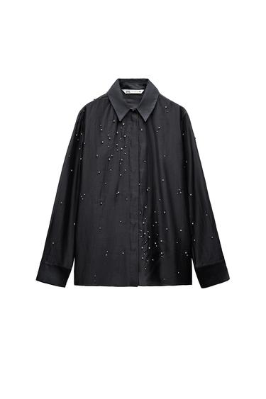 Front view of a black shirt featuring a classic collar and pearl embellishments scattered across the front.