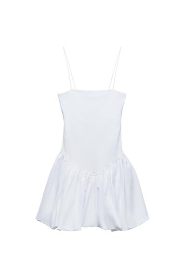 Front view of a white dress with thin straps and a pleated skirt.