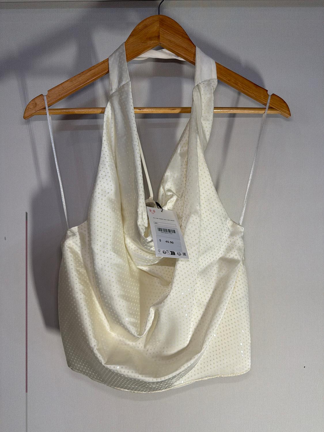 Bright white camisole with spaghetti straps, hanging on a wooden hanger. Visible tag with price of $45.90. Neutral background.