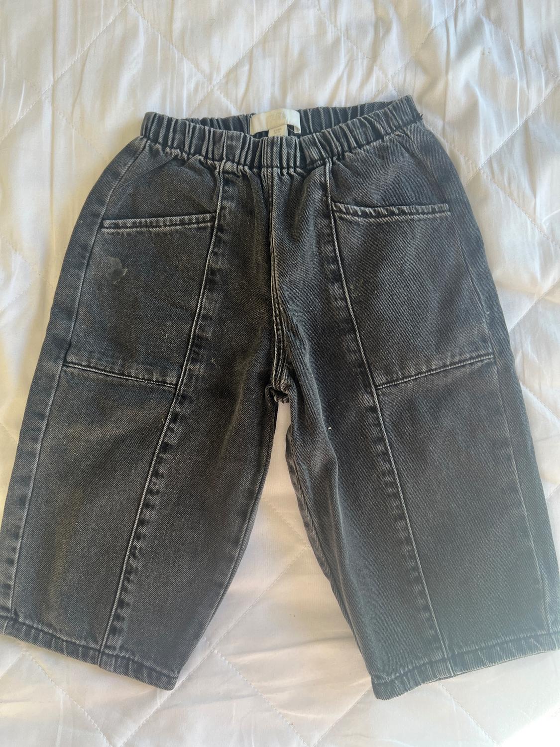 Dark grey denim shorts with an elasticated waist and front pockets, on a white quilted bedspread.