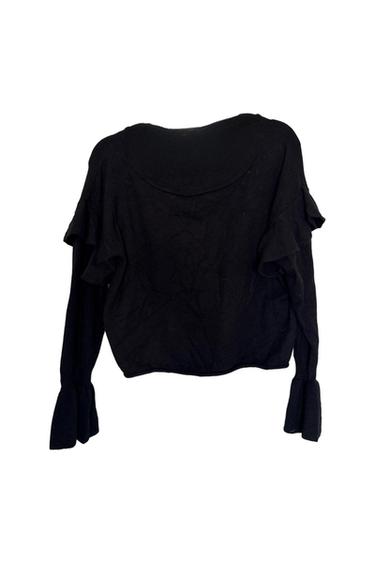 Black long-sleeved blouse with ruffles on the shoulders and cuffs, front view on a white background.