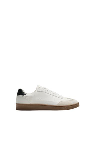 "Side view of a white sports shoe with a brown sole and a black detail on the heel."