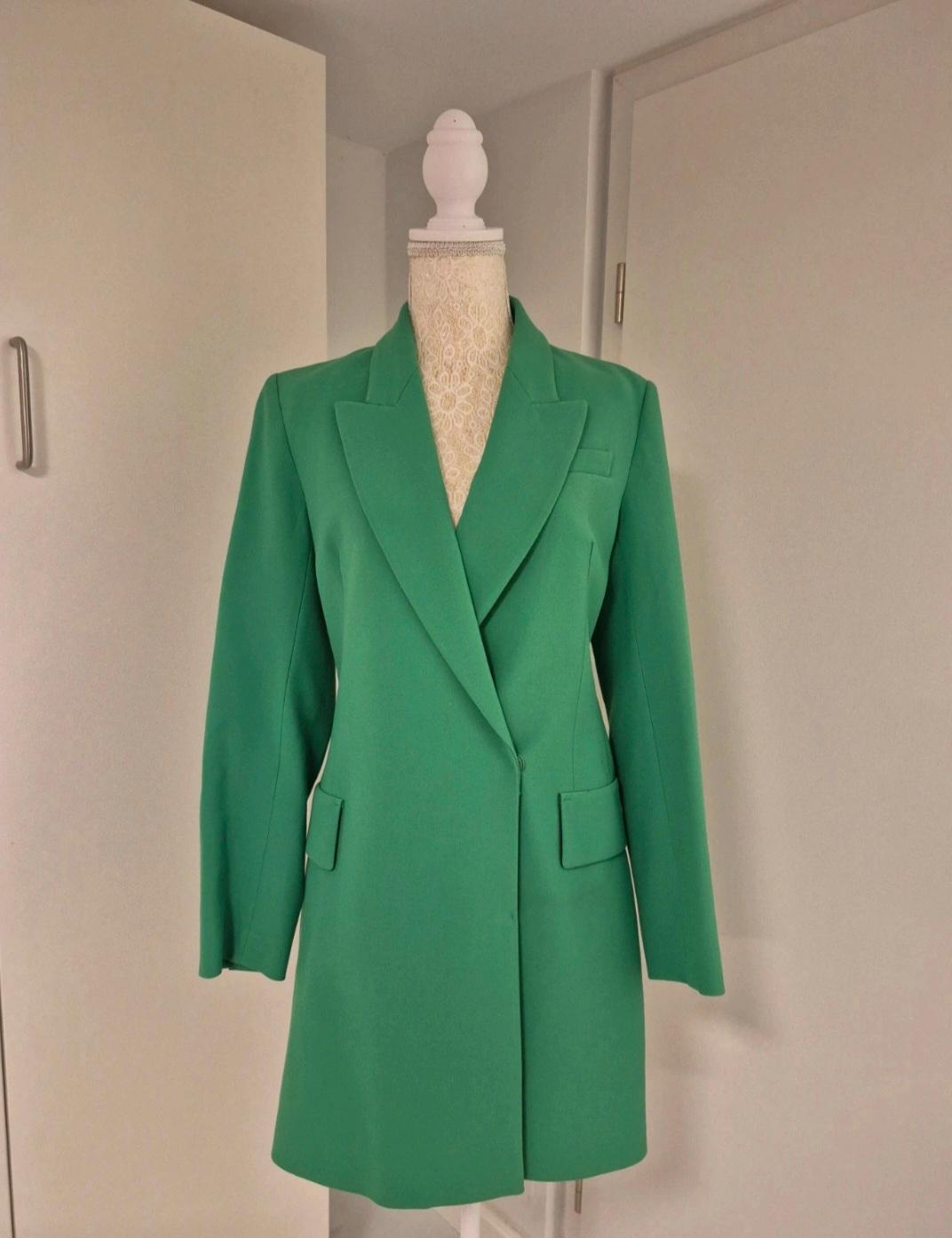 Μاکsιμα / Μακρύ λαχανί σακάκι blazer με φαρδιά πέτα και τσέπες, σε κούκλα βιτρίνας μέσα σε λευκό δωμάτιο.