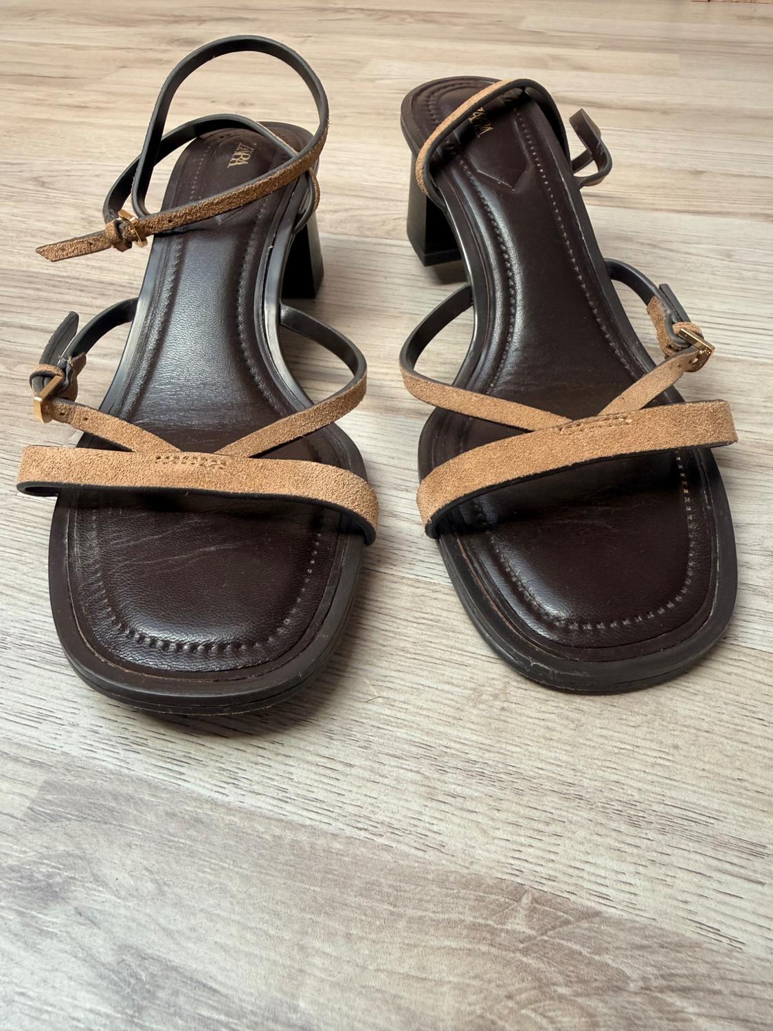 ZARA heeled sandals with a dark brown insole, light brown crossed straps and buckles, on a wooden floor.
