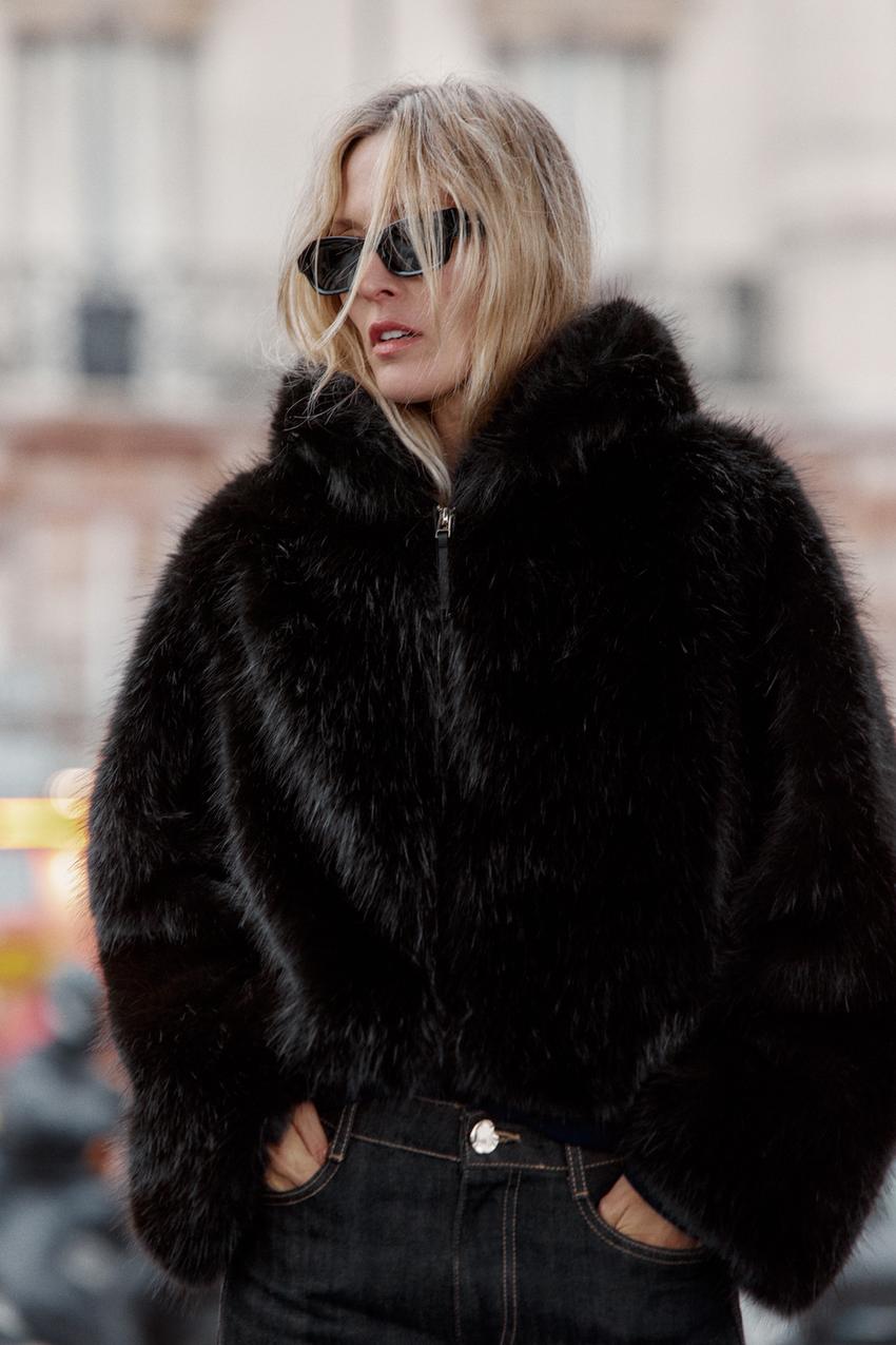 "Medium shot of a black jacket with a faux fur hood, front zipper closure, and side pockets."