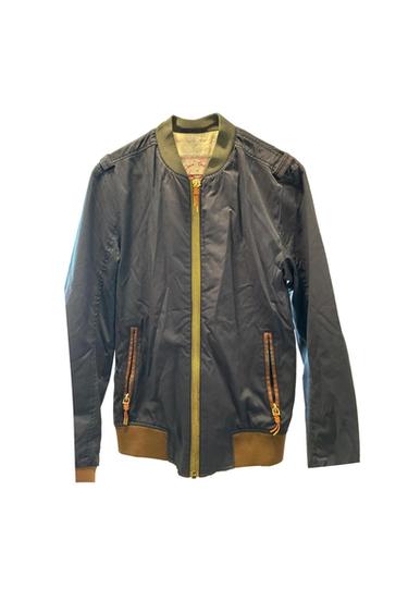 Dark blue bomber jacket with a gold zipper, zippered side pockets, and brown trim at the hem and cuffs.