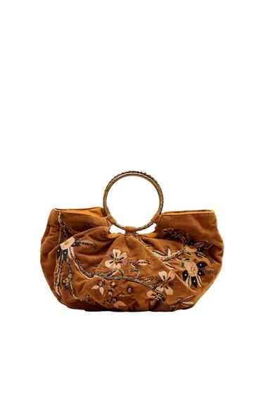Brown bag with floral embroidery and a golden circular handle on a white background. Bohemian design with embossed details.