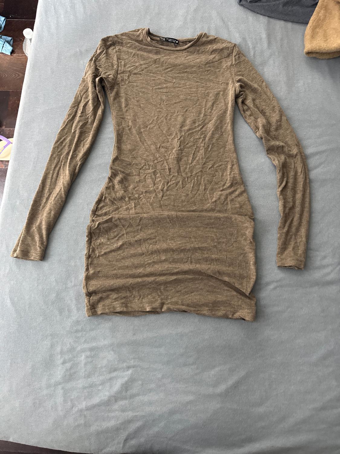 Light brown long-sleeved fitted dress on a grey surface. Wrinkled fabric, casual style.