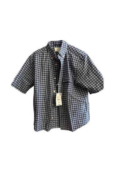 Short-sleeved shirt with a blue and white checked pattern. It features a collar, button fastening at the front, one pocket and a label.