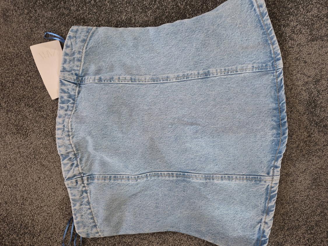 Light blue denim skirt on a grey rug, with a visible label in the top left corner.