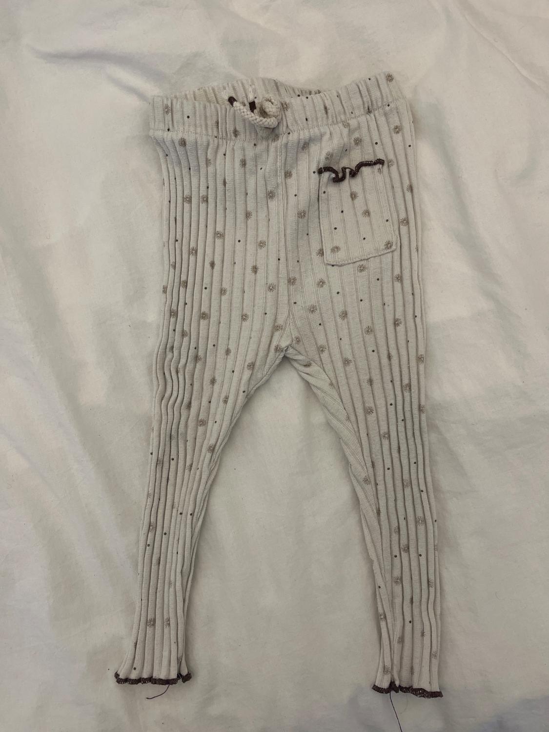 Front view of ribbed children's trousers with a polka dot print and a front pocket. Elasticated waistband with a drawstring.