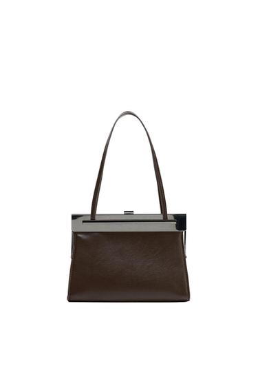 Brown handbag with long handles and a metal clasp at the top, on a white background. Elegant and minimalist design.