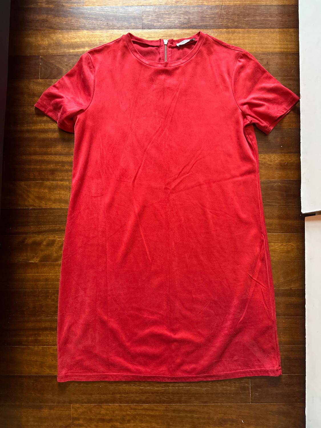 Red short-sleeved, round-neck dress on a wooden floor. The garment is laid out flat and viewed from above.