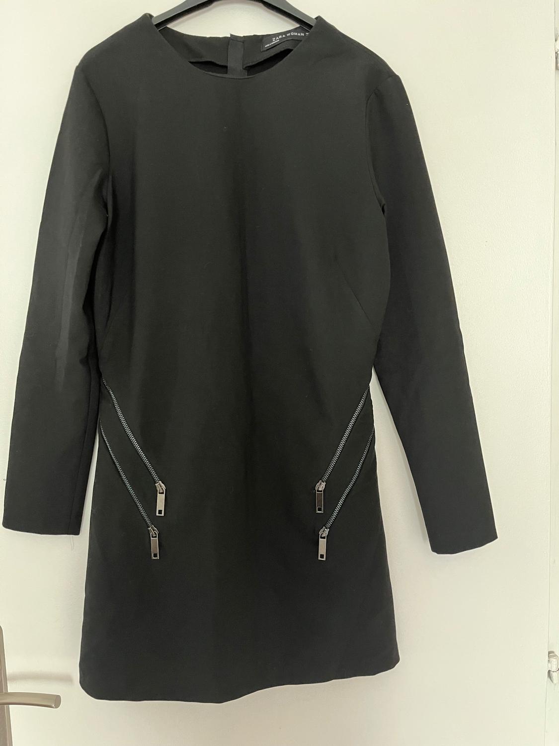 Front view of a black dress with long sleeves and diagonal zips at the bottom.