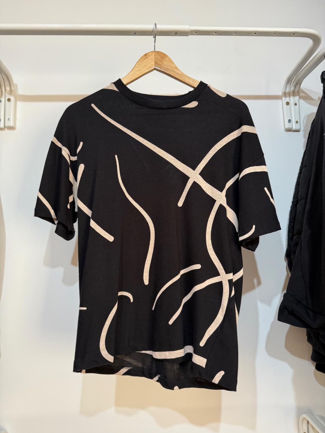 Μπροστινή όψη μαύρου t-shirt με αφηρημένο λευκό σχέδιο.