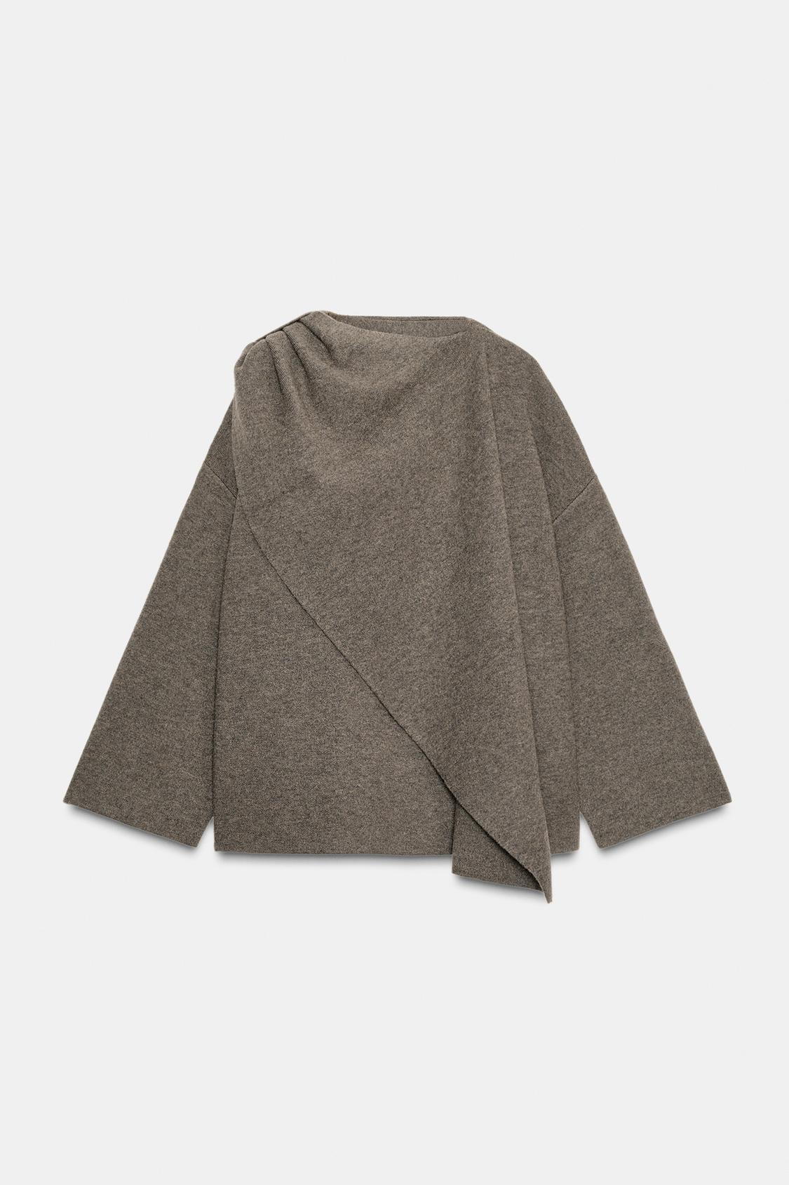 Front view of a grey coat with integrated scarf, long sleeves and a loose fit. Concealed side pockets and a button-fastening wrap closure.