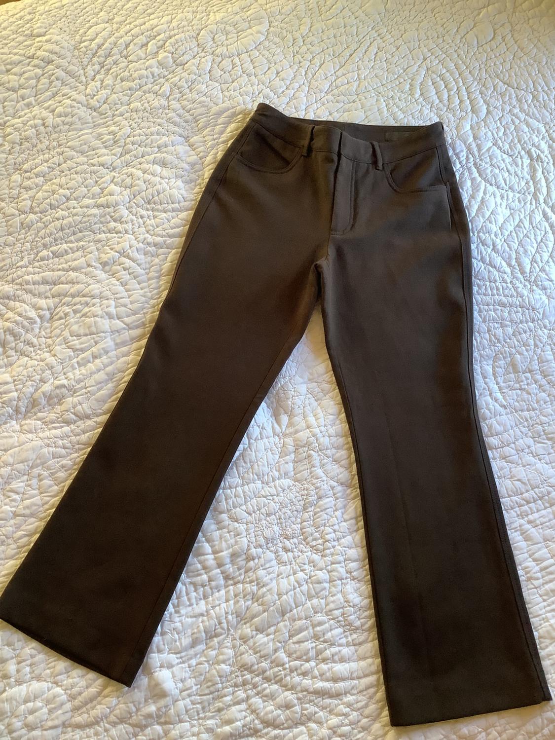 Brown flared trousers on a white quilted bedspread with a patterned design.