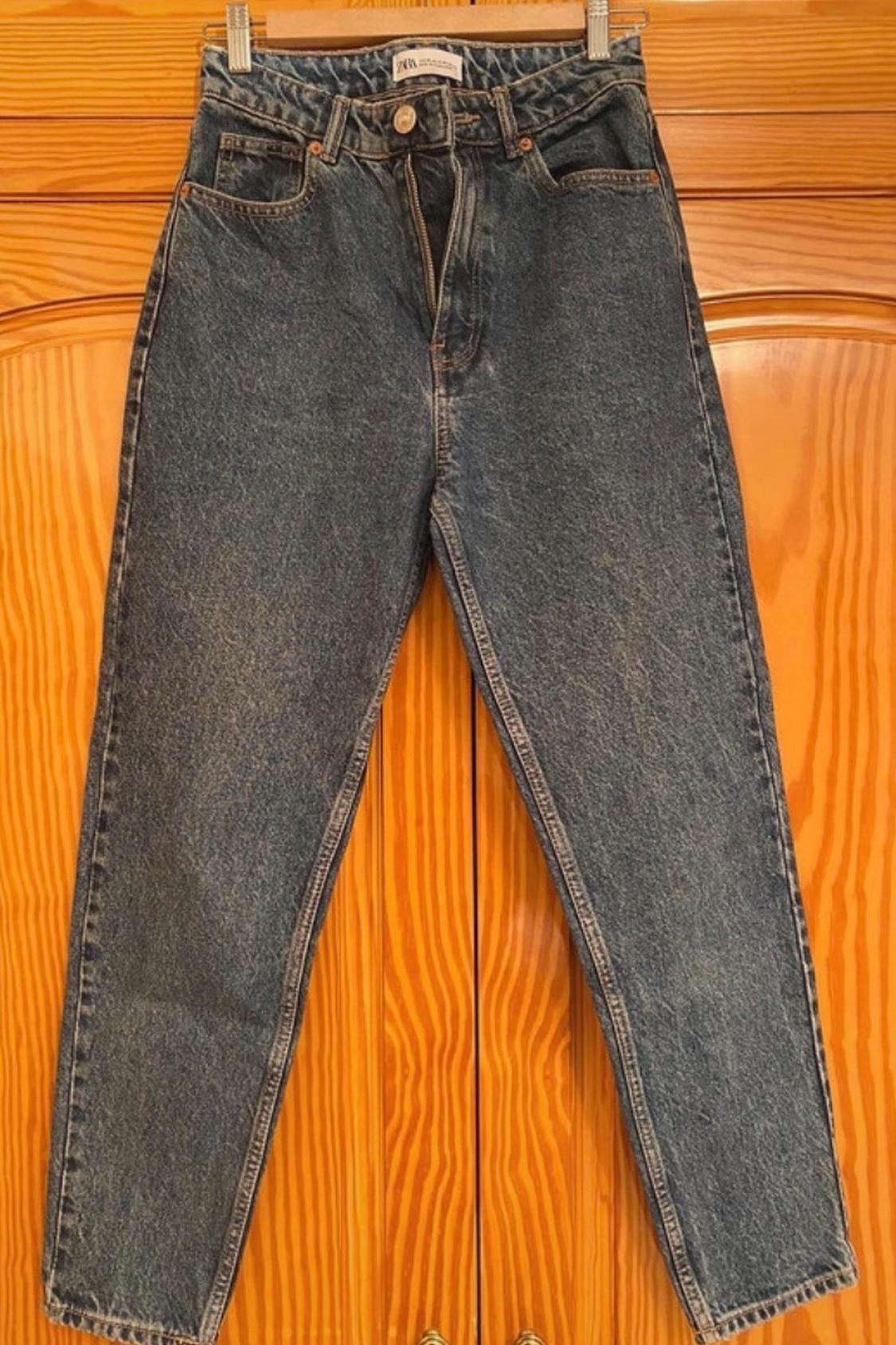 Front view of blue jeans with side pockets and visible metal button.