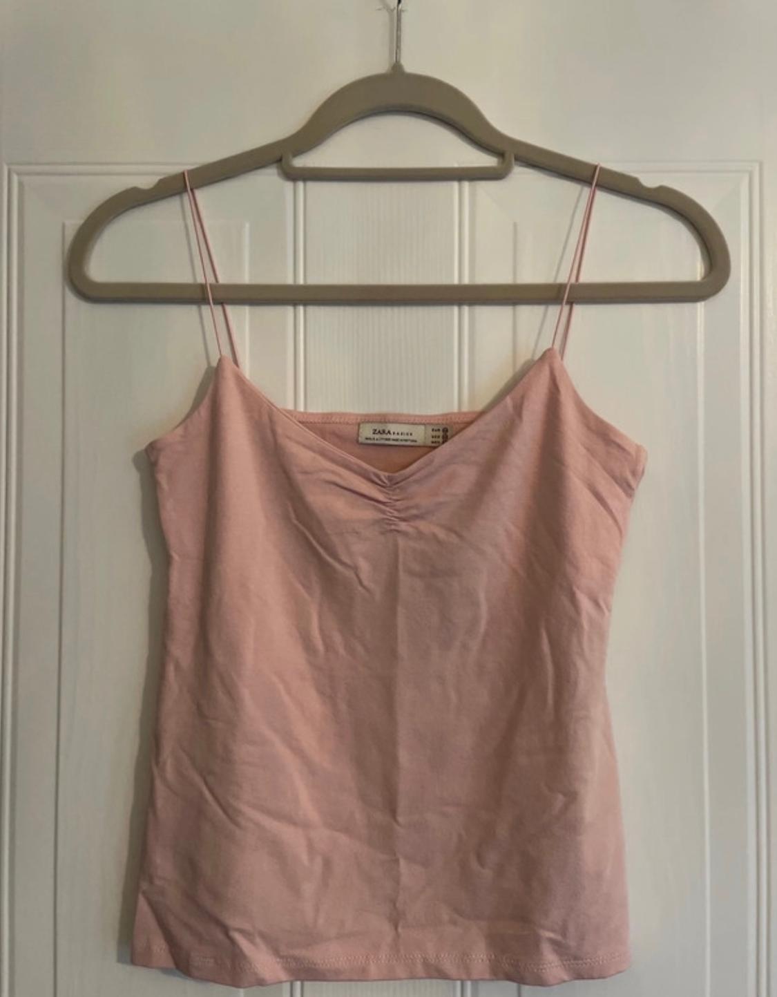 Front view of a pale pink camisole on a hanger.