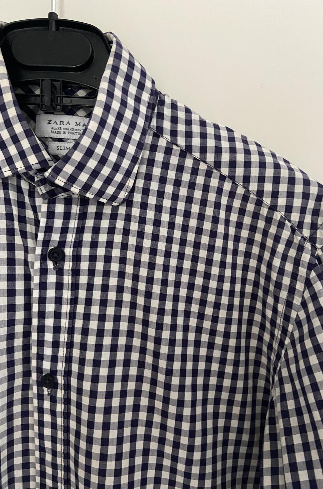 Close-up of a blue and white checked shirt with a classic collar and central button placket.