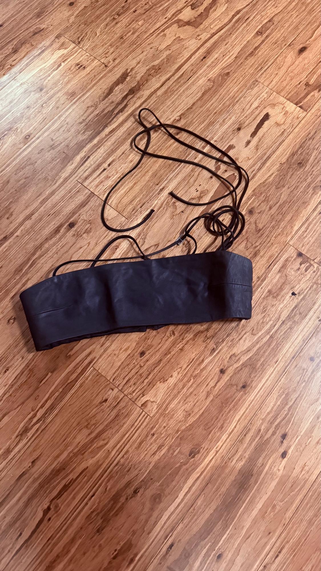 Black top with long, thin ties, placed on a wood floor with grain.
