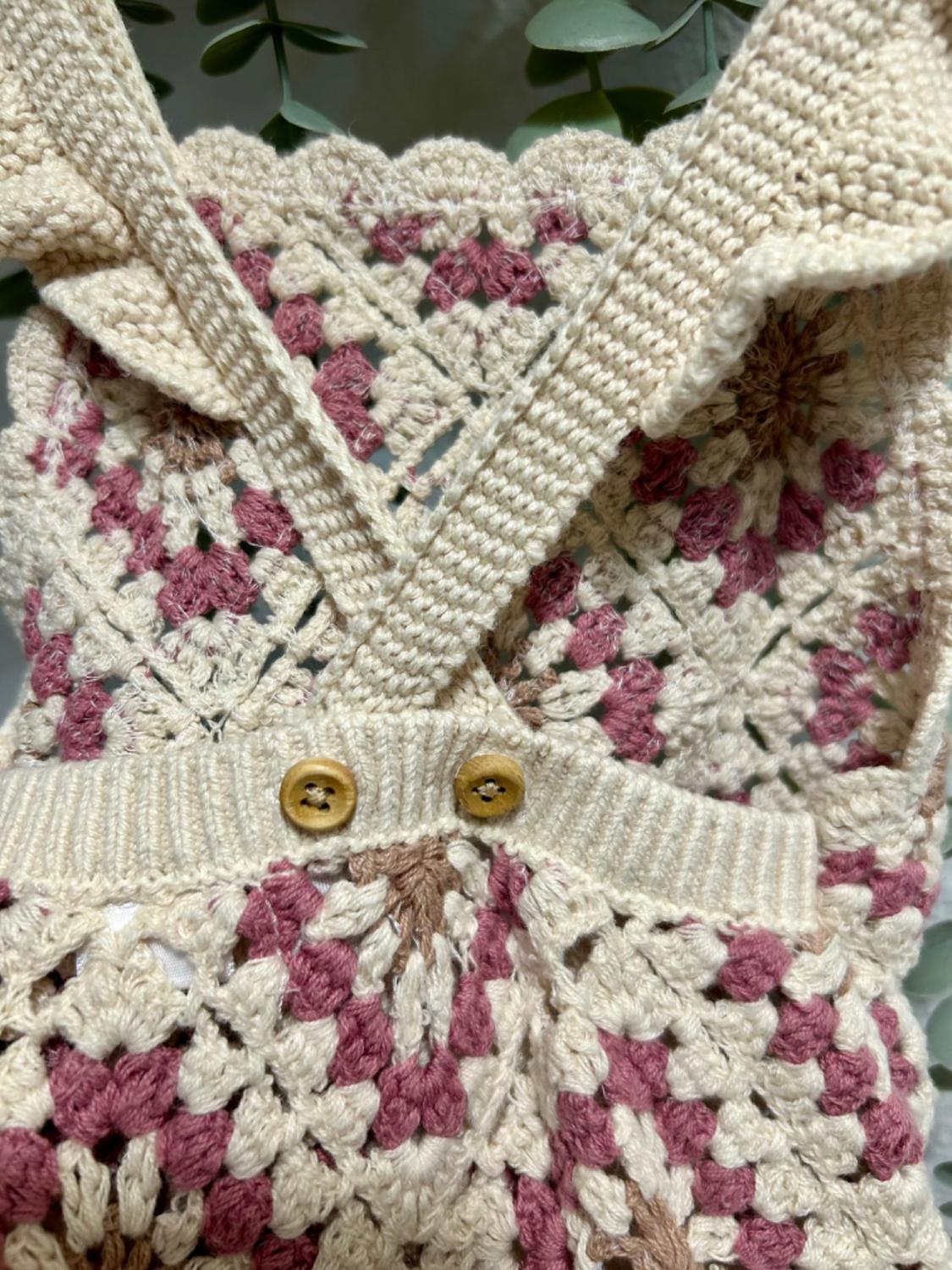 Detail of crochet knit with wooden buttons in beige and pink tones.
