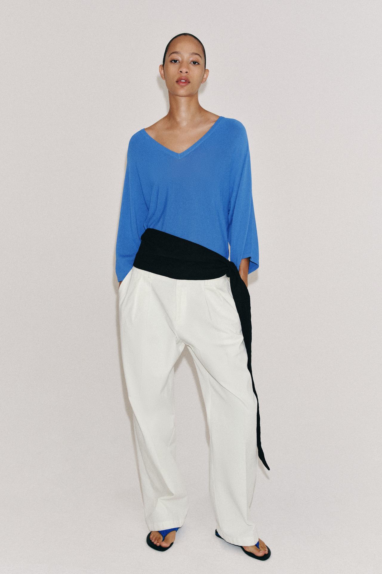 Blue long-sleeved blouse set, white pants with side pockets, and black sandals.