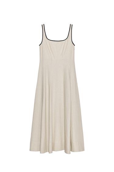 Front view of a light beige midi dress with a round neckline, wide straps, and contrasting black trim.