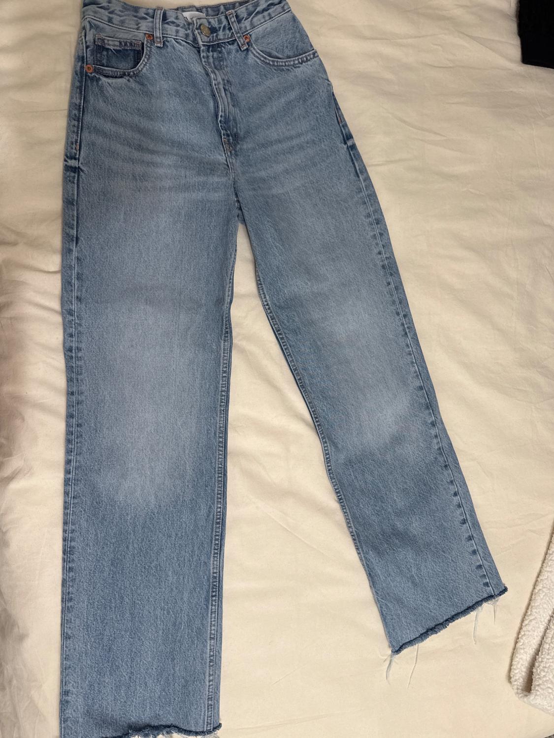 Front view of blue straight-leg jeans with a frayed hem.