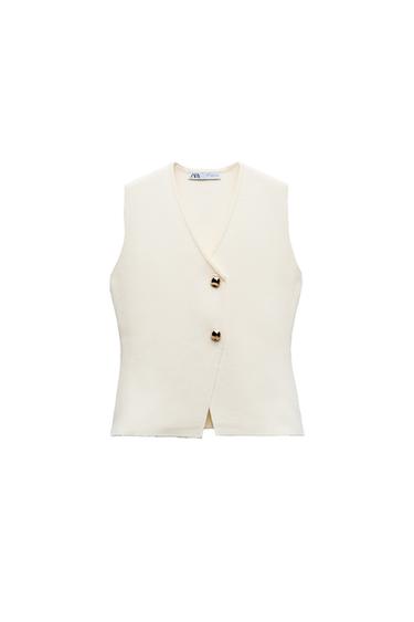 Front view of a cream-coloured sleeveless waistcoat with decorative gold buttons.