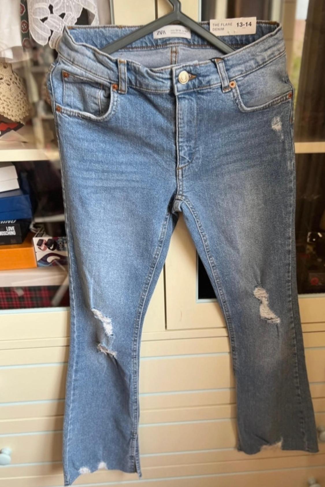 Front view of blue jeans with rips and visible front pockets.