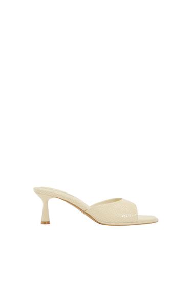 Low-heeled beige sandal with interwoven texture on a white background. Elegant and minimalist design.