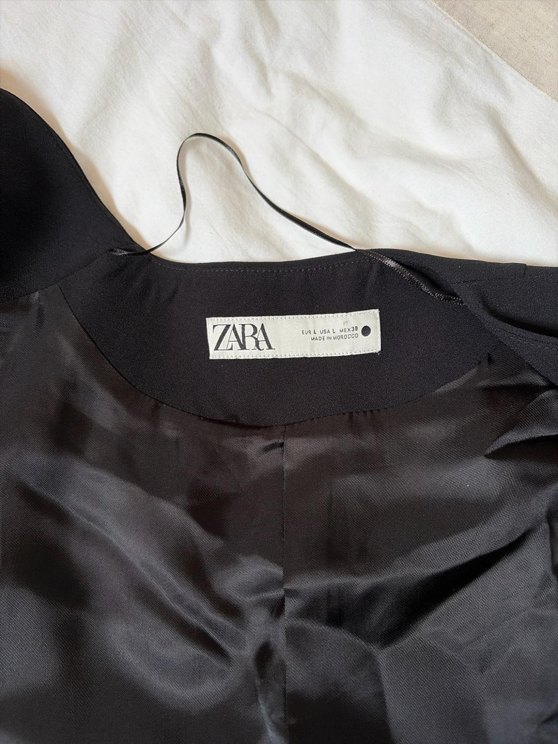 Detail of the interior of a black garment. White label with the text: ZARA EUR L USA L MEX30 MADE IN MOROCCO.