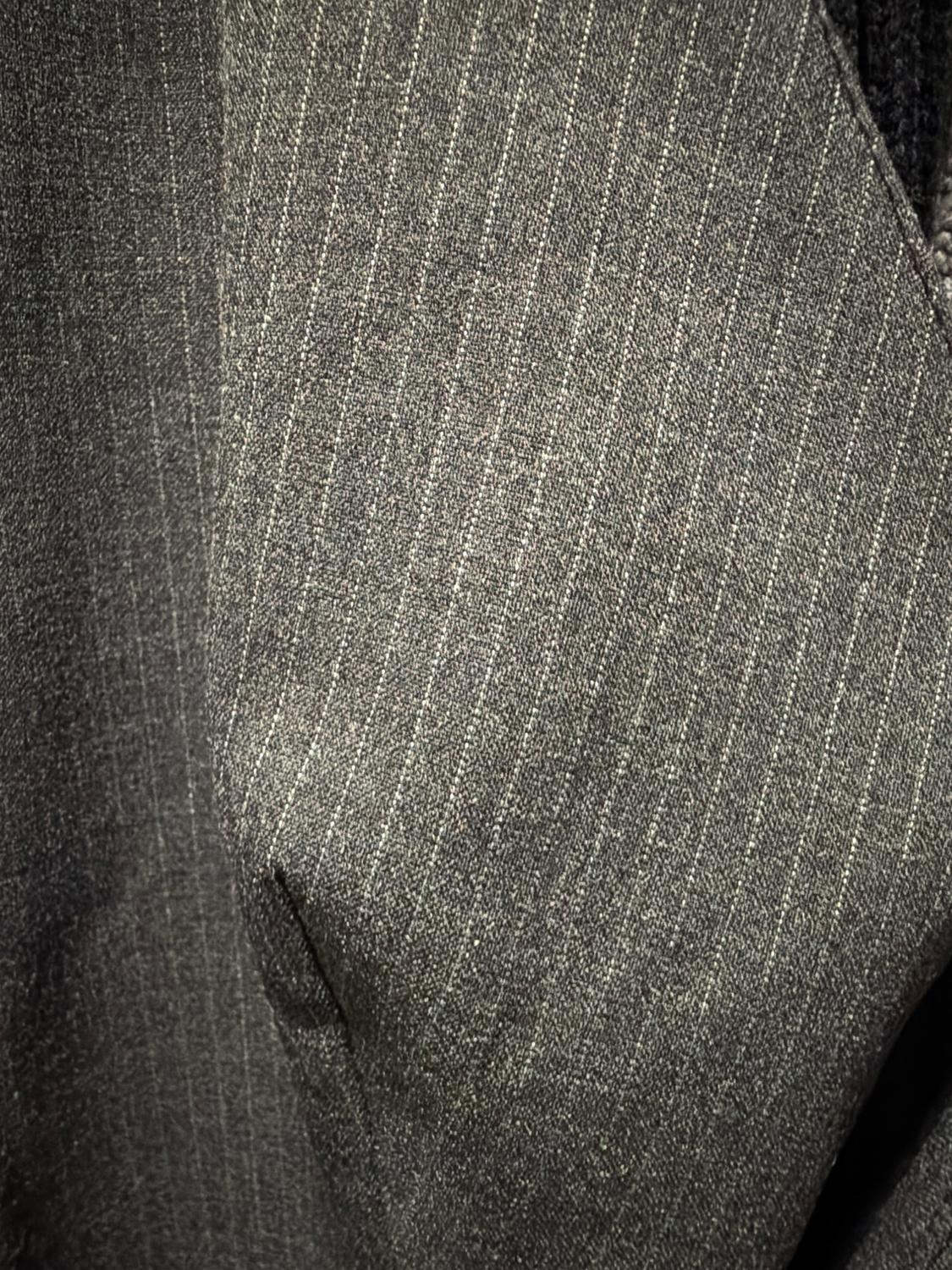 Gray fabric with thin white vertical lines, soft texture, and striped pattern. Close-up of an elegant and classic textile.