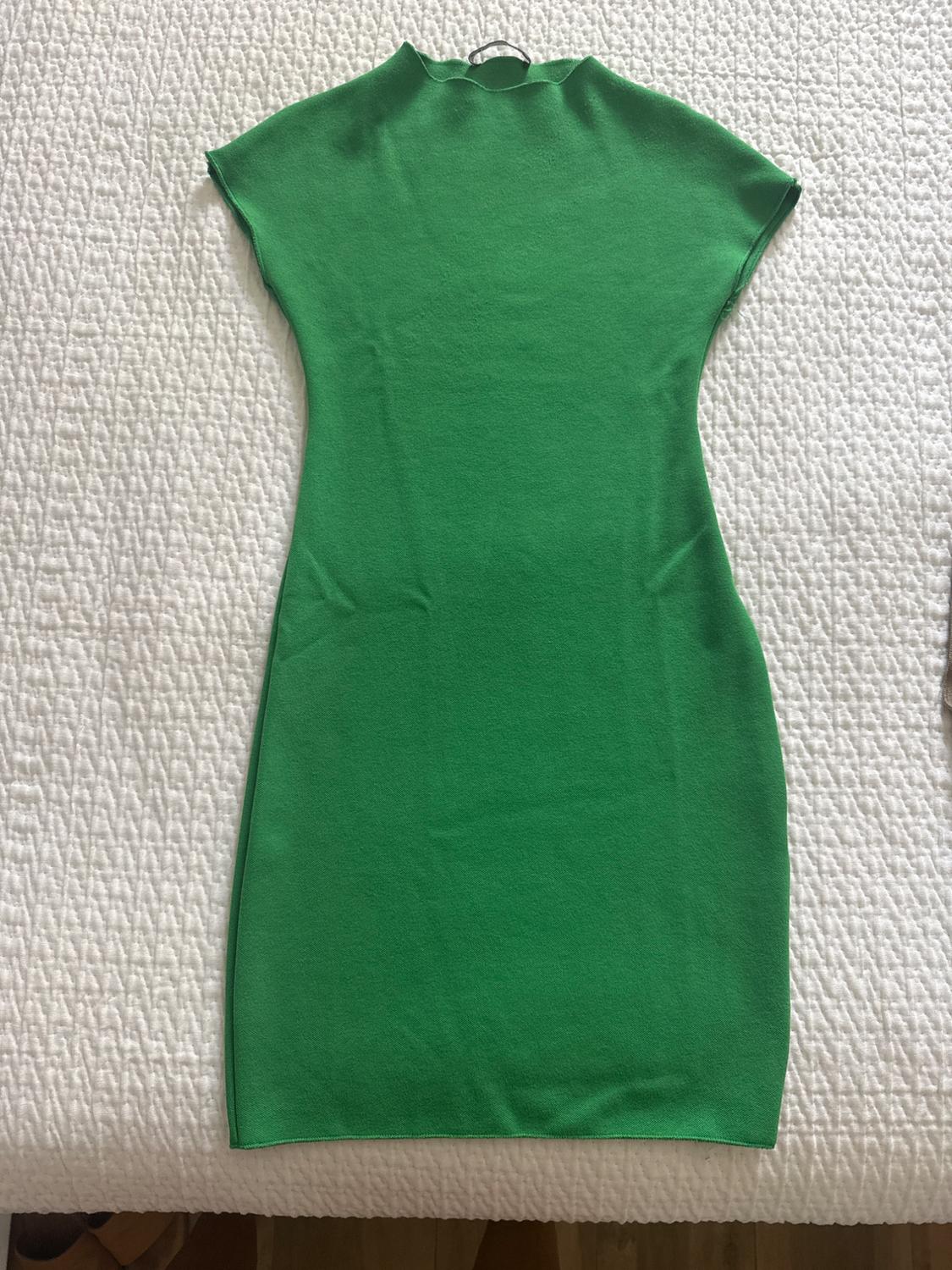 Short-sleeved green dress on a textured white bedspread.