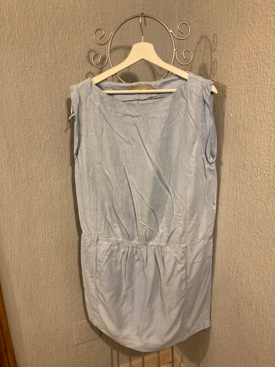 Front view of a light blue sleeveless dress with a ruched waist and a round neck.