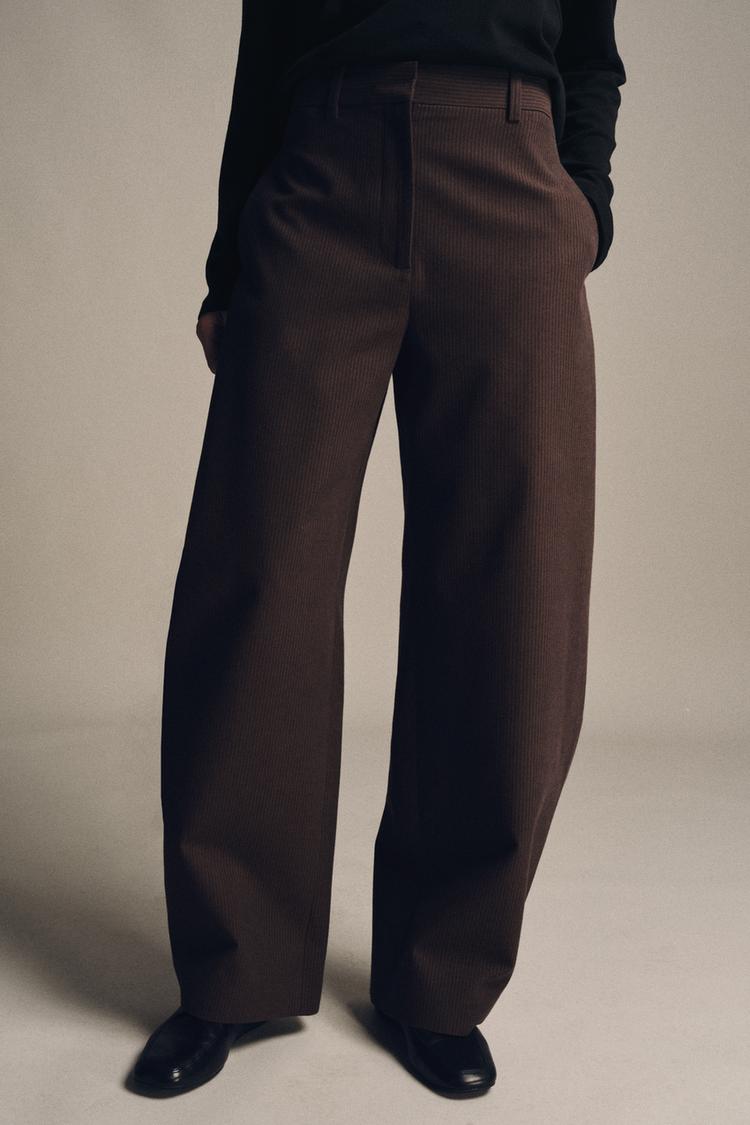 Mid-shot of brown marl trousers with stripes, mid-rise, concealed side pockets and wide leg. Front zip fastening.