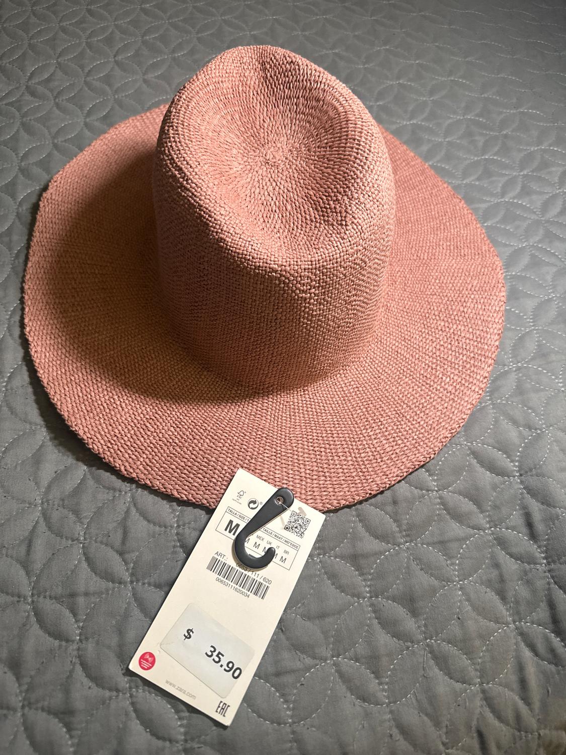 Pink hat on gray comforter with a price tag of $35.90. Tag shows size M and barcode.